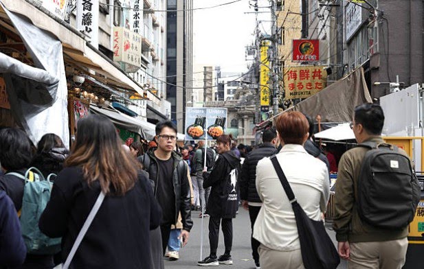 Tsukiji Outer Market narrow lanes filled with seafood vendors, sushi stalls, and local food shops in the early morning, Tokyo